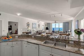 A spacious kitchen with granite countertops, white cabinetry, and a large island with a sink. - Beachfront Condo + Resort Pool + Spa Amenities + Movie Theater + Game Room (Panama City Beach)