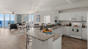 Una cocina moderna con armarios blancos, encimera de granito y una isla central con fruta.