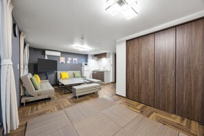 A modern living room with a sofa, ottoman, and a large wooden wardrobe.