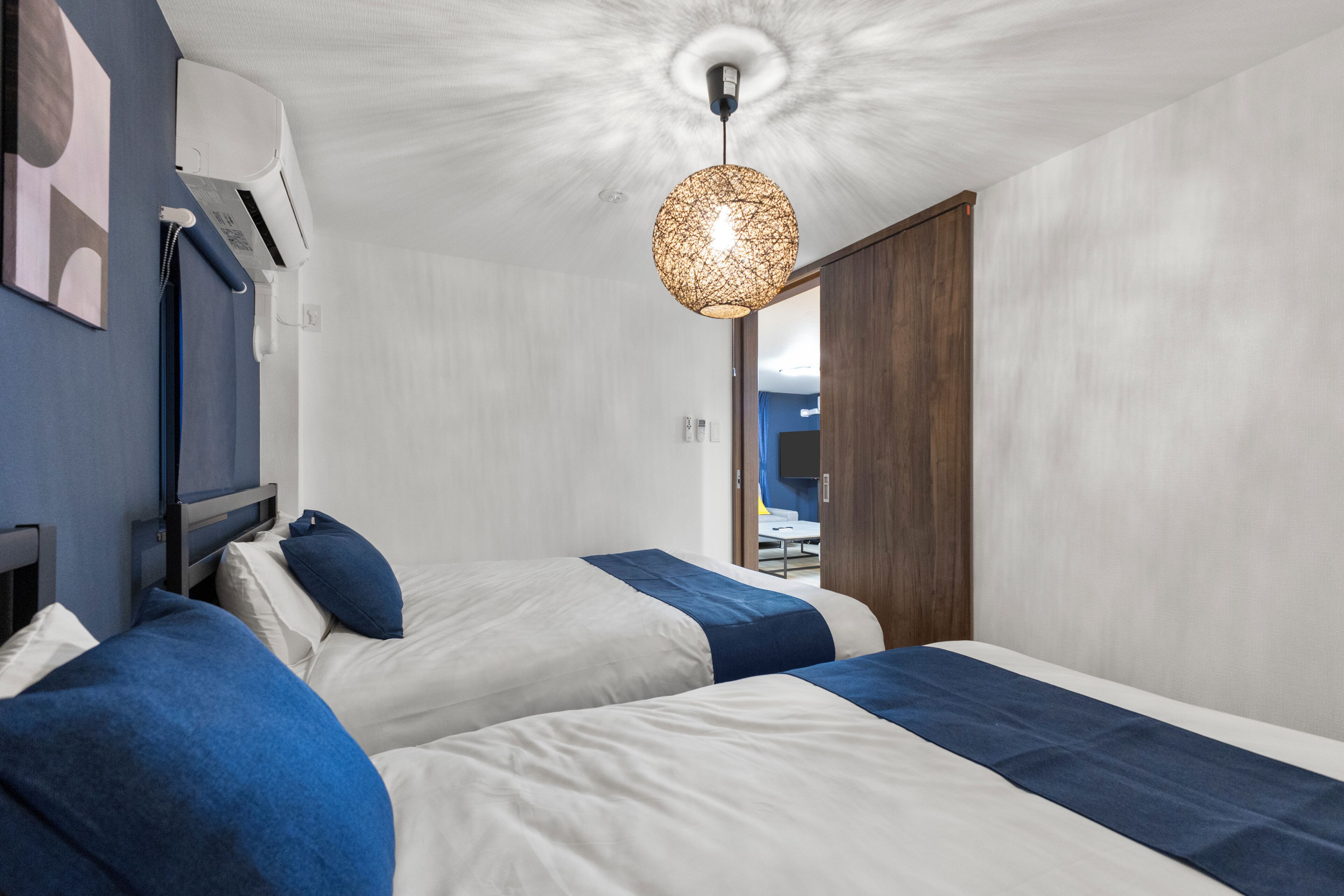 A modern hotel room with two beds, a ceiling fan, and a view of the outdoors.