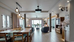 Un'ampia sala da pranzo con un tavolo e sedie in legno, una ventola a soffitto e lampade a sospensione.