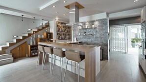 Una cucina moderna con isola centrale, sgabelli da bar, una scala e vista all'esterno.