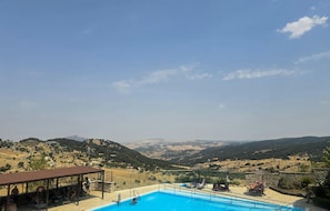Zona de piscina con vistas a un valle y colinas.