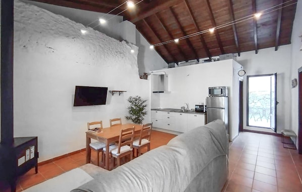 Un espacio habitable compacto con comedor, kitchenette y sofá.