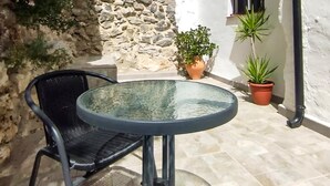 Ein Tisch mit Glasplatte und ein Stuhl in einem Innenhof mit Steinwänden.