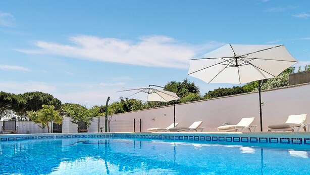 Una piscina con sillones de playa y sombrillas.