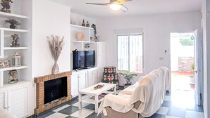 Una sala de estar con chimenea, televisor, sofá y ventilador de techo.