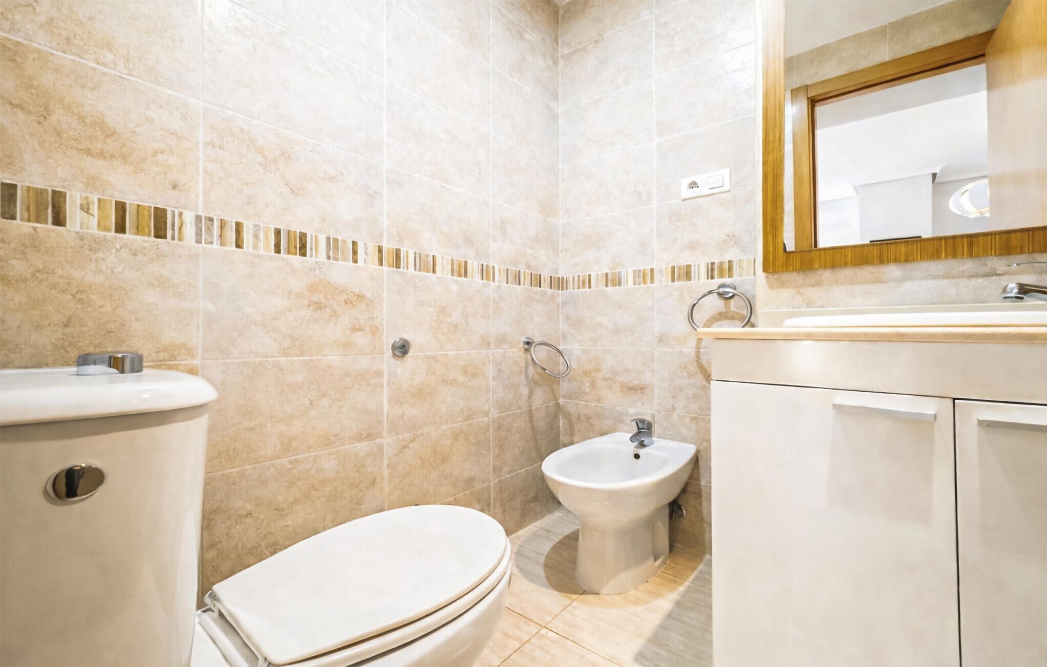Un baño con inodoro, bidé y lavamanos.