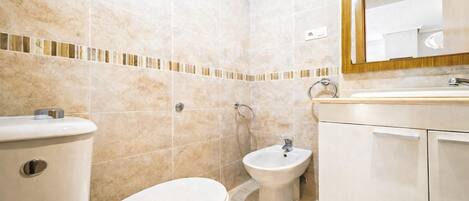 Un baño con inodoro, bidé y lavamanos.