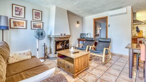 Ein Wohnzimmer mit Kamin, zwei Ledersesseln, einem Holztisch und einer Couch.