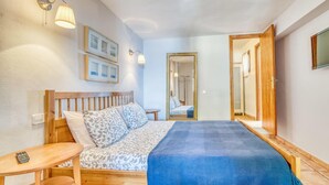 Ein Schlafzimmer mit einem hölzernen Bett, einem Nachttisch, einem Spiegel und Wandleuchten.