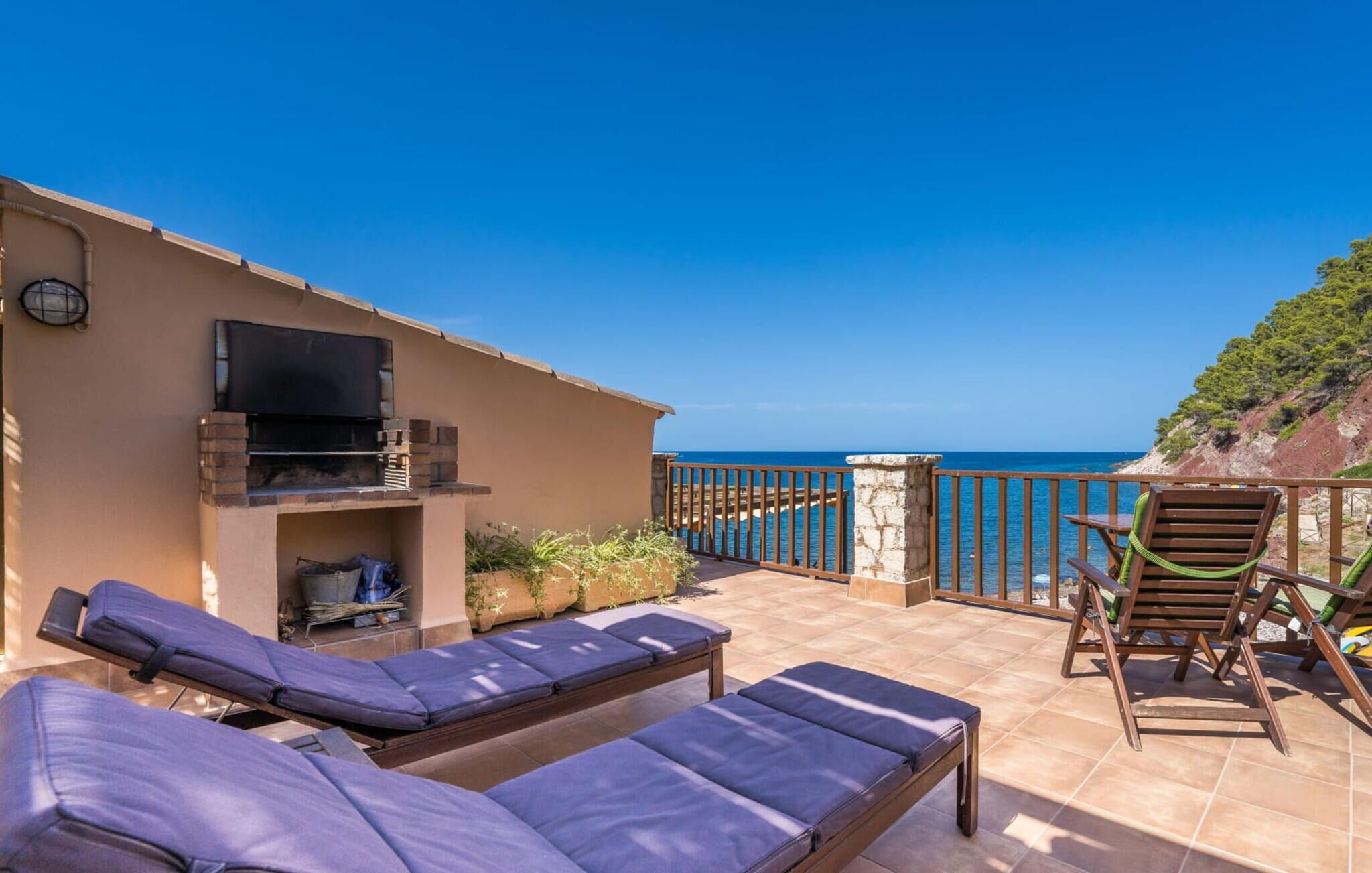 Una terrazza con poltrone da relax, un barbecue e un televisore.