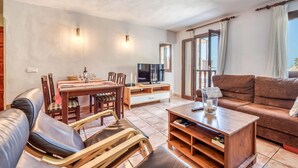 Ein Wohnzimmer mit einem Holzesstisch, Stühlen, einer Couch und einem Fernseher.