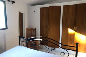 Ein Schlafzimmer mit einem Bett, einem Sessel und Holzschränken.