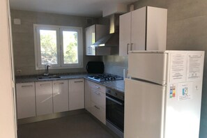 A kitchen with white cabinets, a gas stove, a built-in oven, and a refrigerator. - Classy Holiday Home in Santa Cristina d'Aro (Santa Cristina d'Aro)
