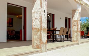 An outdoor dining area with a table and chairs, a red door, and a view of the interior. - Beautiful home in Marratxí with private swimming pool, can be inside or outside (Marratxí)