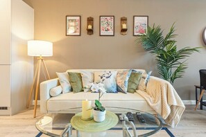 A living room with a sofa, a coffee table, a lamp, and wall-mounted artwork. - City Centre Birmingham 1-Bed with WiFi and Parking (West Midlands)