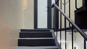 A staircase with black handrails and a door at the top. - Omeli Homestay (Hanoi)