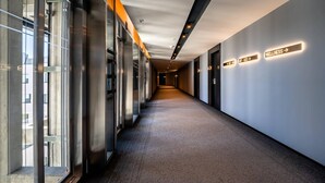 Un couloir avec des portes en verre d’un côté et des panneaux de signalisation de l’autre.
