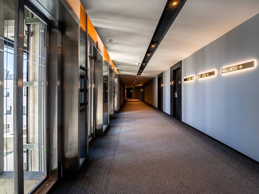 A corridor with glass doors on one side and directional signs on the other.