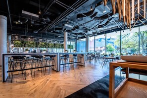 A modern cafe interior with high ceilings, exposed ductwork, and a mix of bar and dining areas. - Clarion Congress Hotel Brno (Brno)