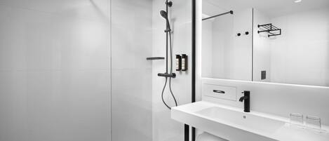 A modern bathroom with a glass shower enclosure, a white sink, and a large mirror.