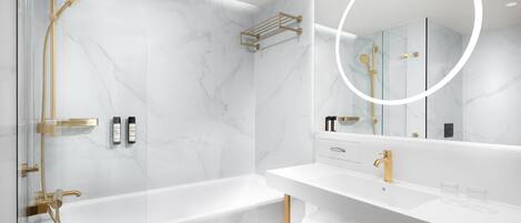 A modern bathroom with a marble floor, a bathtub, a shower with gold fixtures, and a vanity with a mirror.
