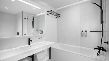 Un baño moderno con un tocador blanco, un espejo grande, una ducha con cabezal de ducha manual y un perchero para toallas.
