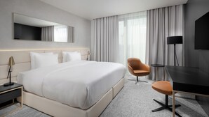Une chambre d’hôtel moderne avec un grand lit, un bureau, une chaise et un téléviseur.