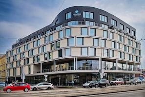 Ein modernes Hotel mit einer geschwungenen Fassade, großen Fenstern und einem markanten Eingang.