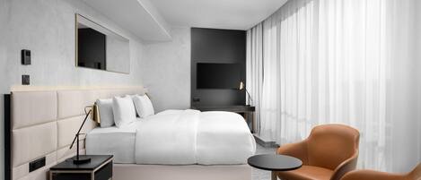 Una habitación de hotel moderna con una cama grande, televisión, escritorio y una silla.