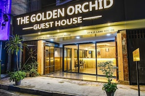 Η εξωτερική όψη του The Golden Orchid Guest House διαθέτει μια μοντέρνα είσοδο με γυάλινες πόρτες, έναν χώρο υποδοχής που είναι ορατός μέσα από το γυαλί και γλάστρες με φυτά στην είσοδο.