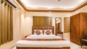 Un dormitorio con cabecera de madera, cama con almohadones estampados, mesita de noche, espejo y armario.