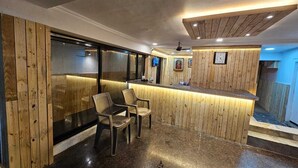 Un interior moderno con un mostrador de recepción de madera, dos sillas y un ventanal grande.