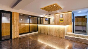 Un área de recepción con paneles de madera, un mostrador de recepción y un reloj en la pared.