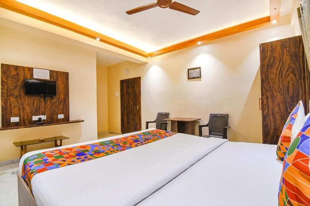 A hotel room with a bed, a desk, a chair, a television, and a ceiling fan.
