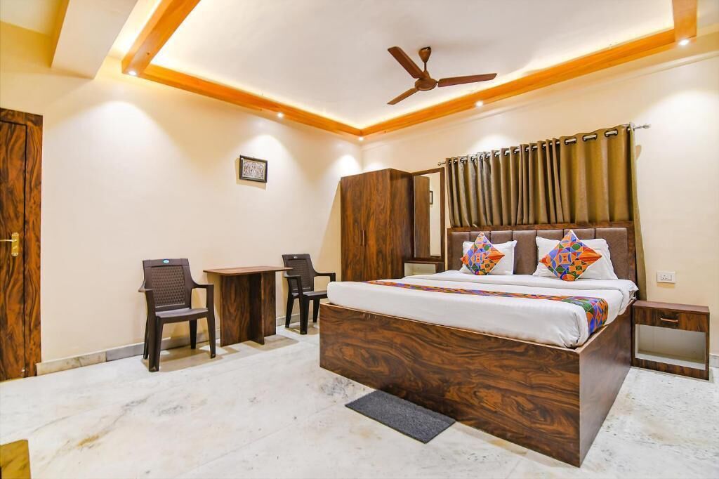 A bedroom with a bed, a desk, a chair, a wardrobe, and a ceiling fan.