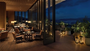 A modern hotel lobby with a wooden ceiling, large windows, and a view of the city at dusk. - The Dali EDITION (Dali)