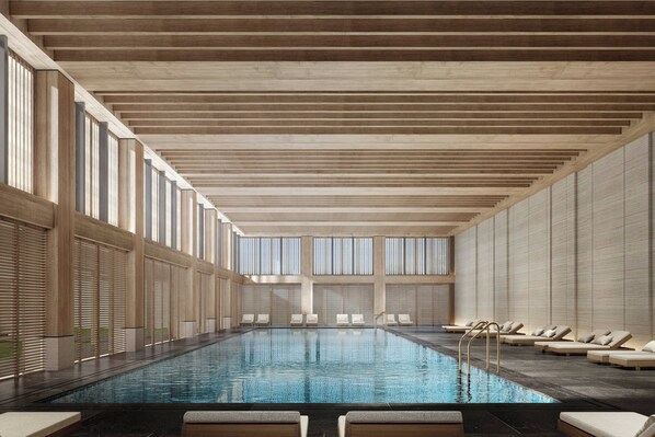 Piscina interior moderna com design alongado, grandes janelas e espreguiçadeiras nas laterais.