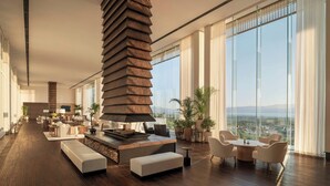 A modern interior with a fireplace, seating area, and large windows offering a city view. - The Dali EDITION (Dali)