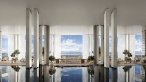 A modern hotel lobby with a reflective pool, large windows, and a seating area with plants. - The Dali EDITION (Dali)