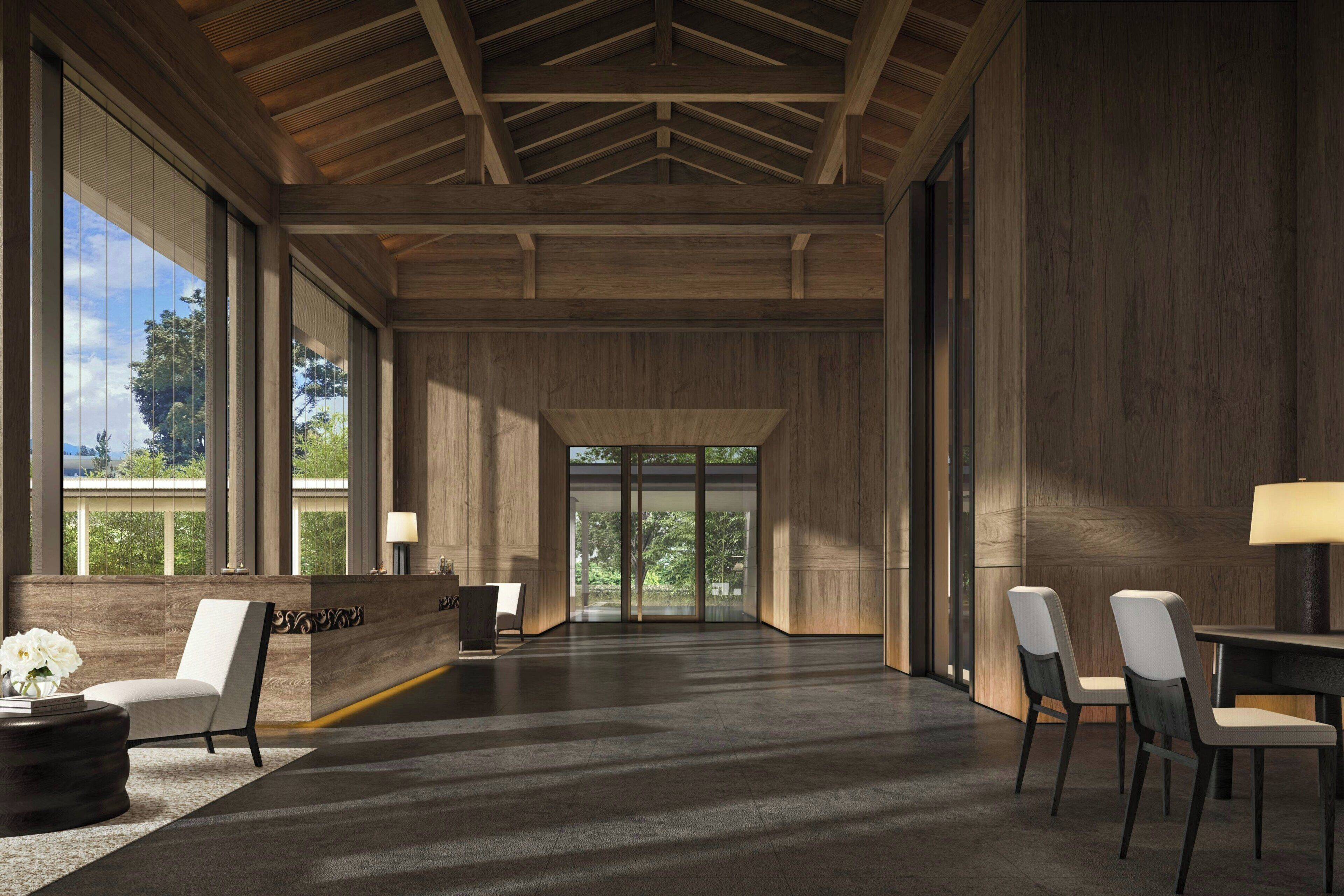 A spacious lobby with a wooden ceiling, large windows, a reception desk, and a seating area.
