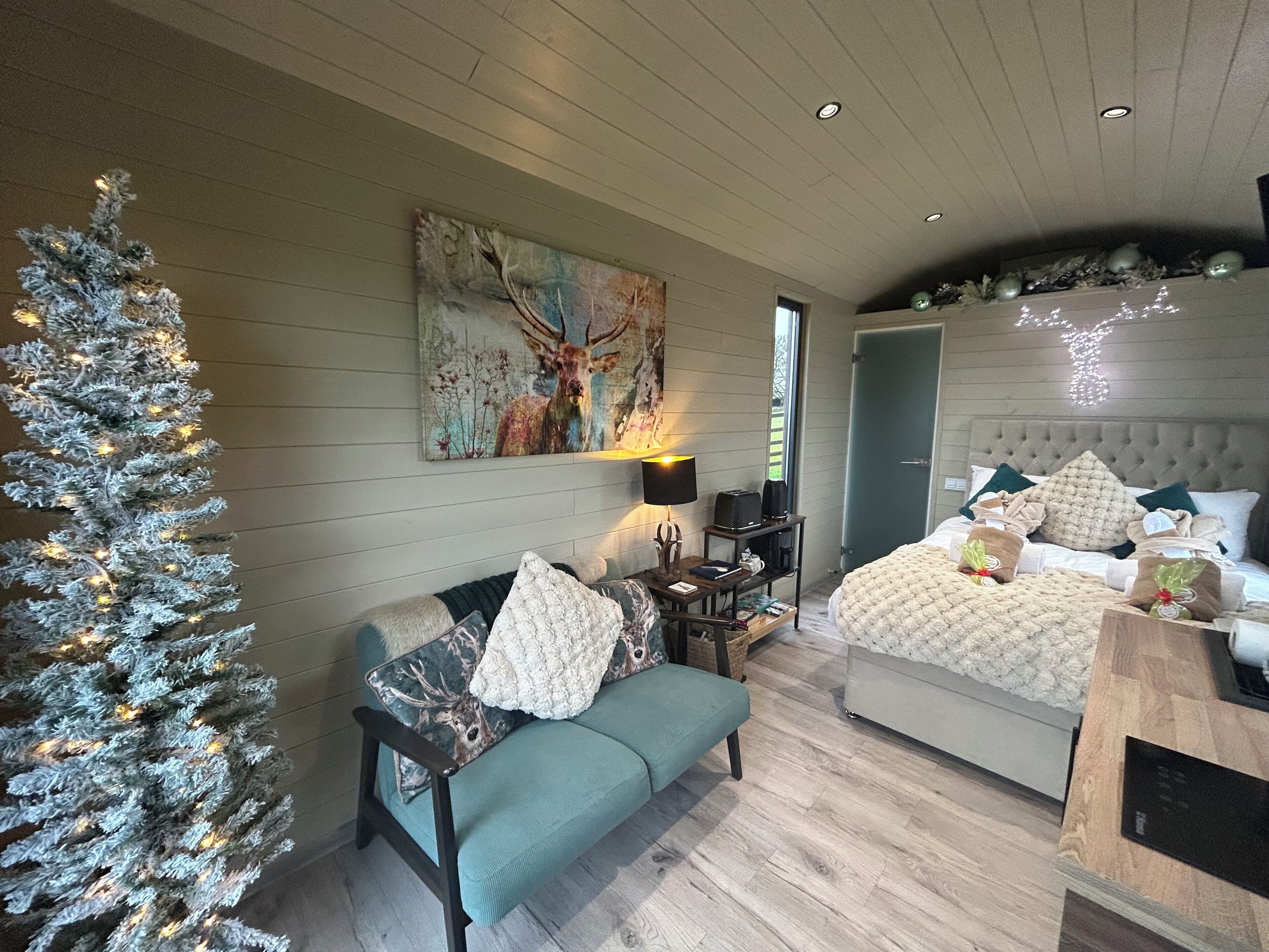Een gezellige slaapkamer met een groot bed, een kleine zithoek, een kerstboom en een schilderij aan de muur.