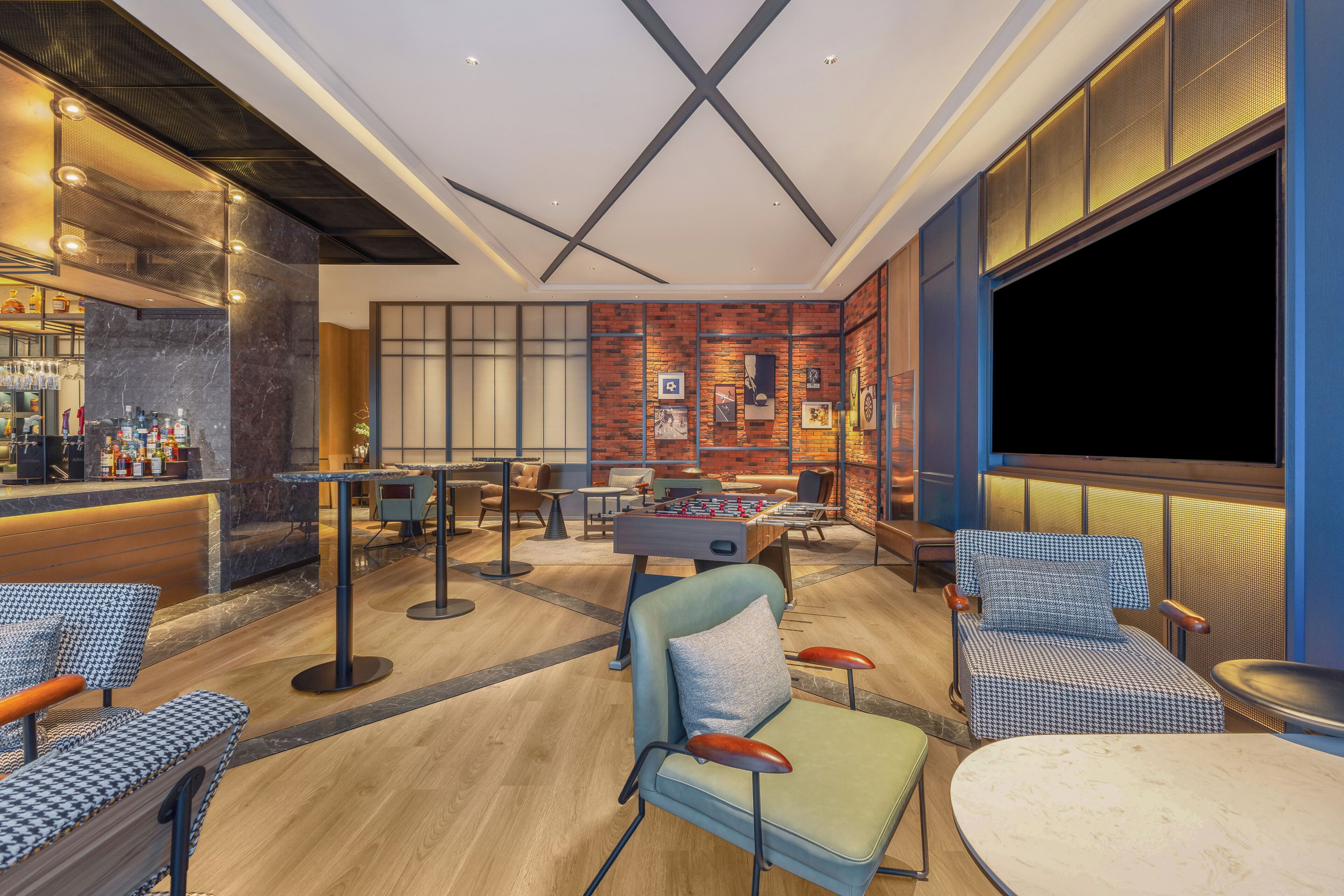 A modern lounge area with seating, a bar, and a foosball table.