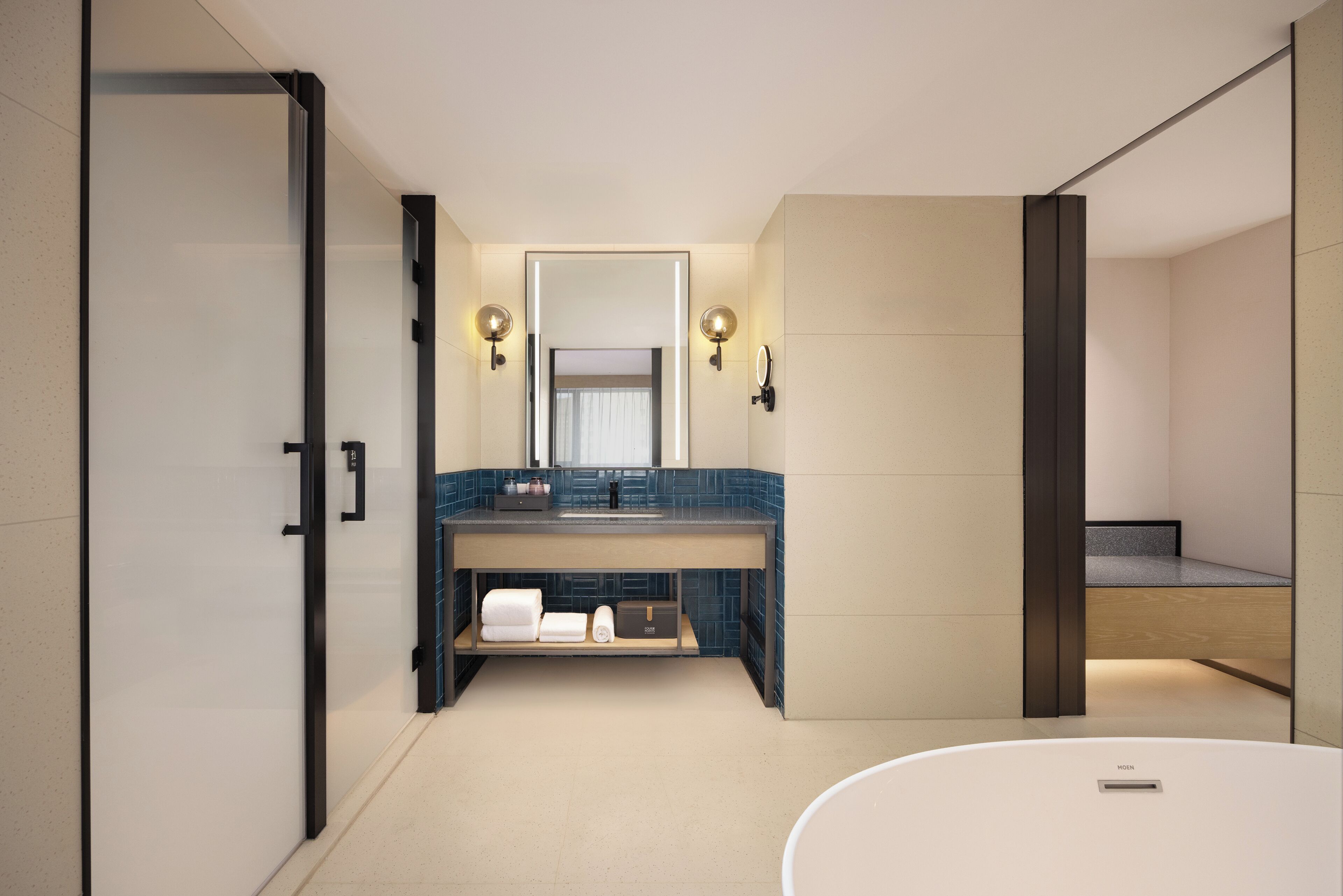 Un baño moderno con un espejo grande, un lavabo con toallero y una zona de ducha independiente.