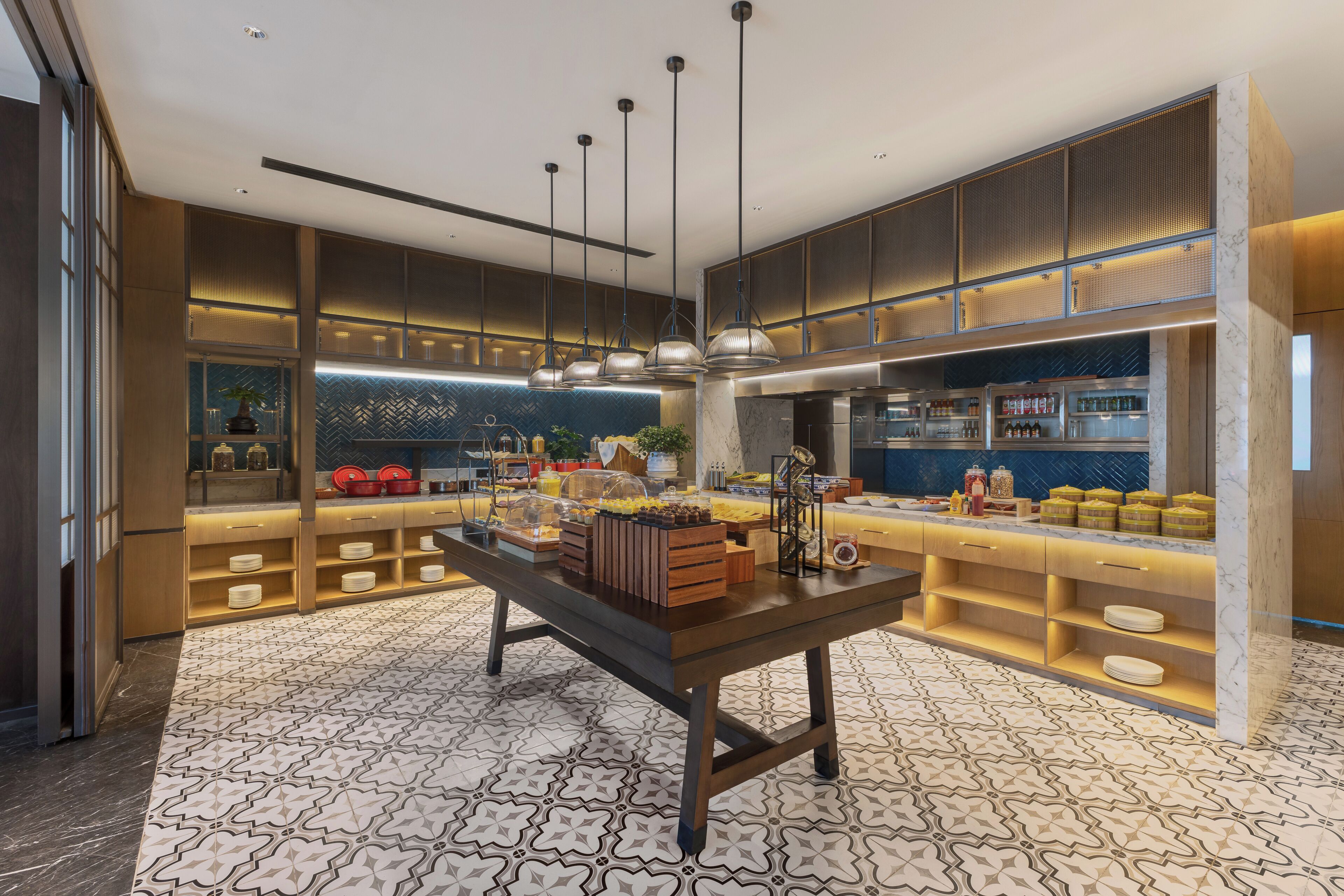 A modern kitchen with a marble countertop, pendant lighting, and a buffet setup.