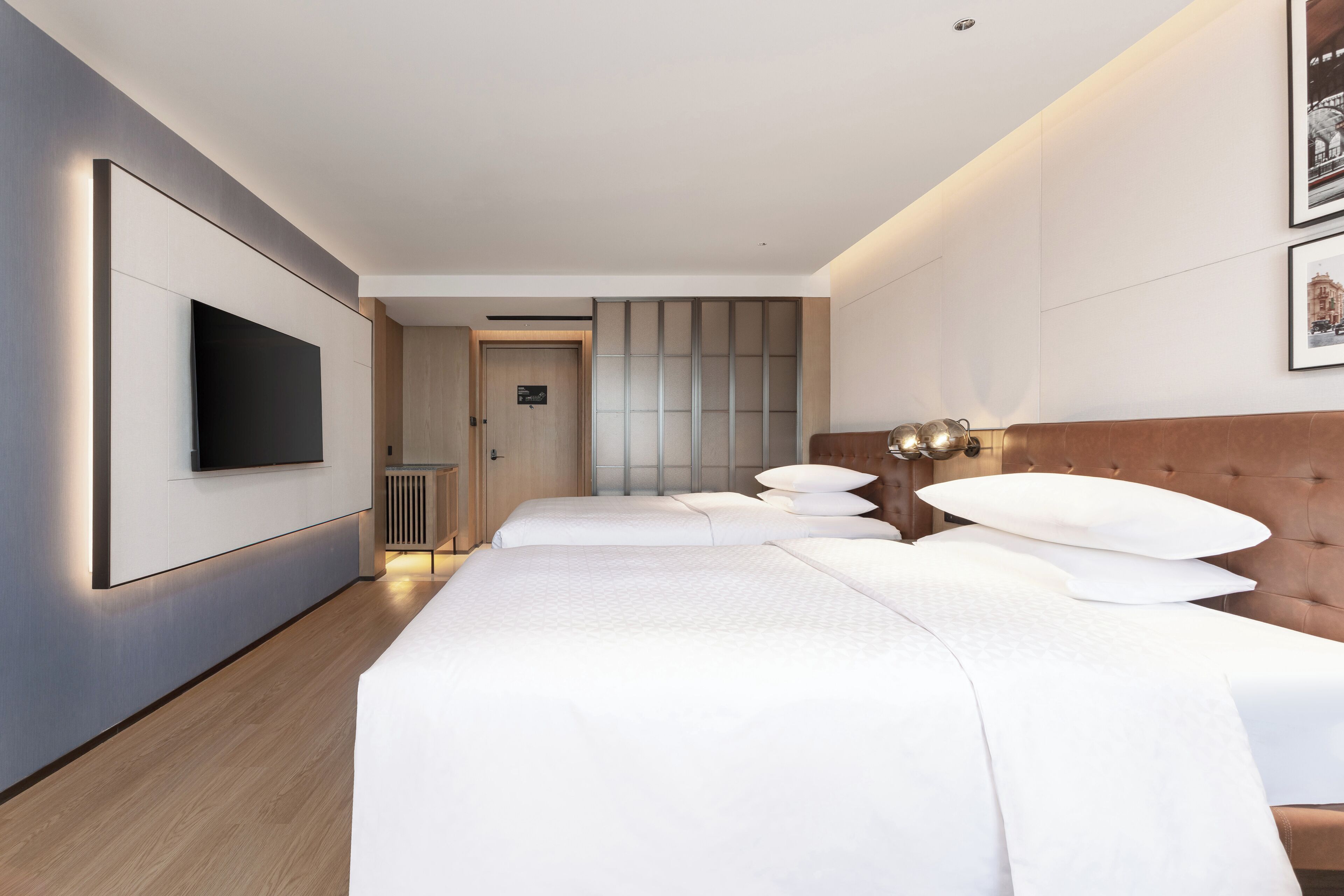 A hotel room with a large bed, a flat-screen TV mounted on the wall, and a door leading to a bathroom.