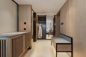 A modern hotel room with a wooden floor, a bench, a small table, and a wardrobe.
