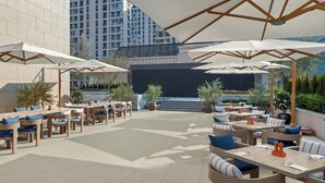 An outdoor patio area with multiple tables and chairs, large umbrellas, and potted plants. - Four Points by Sheraton Qingtian (Lishui)