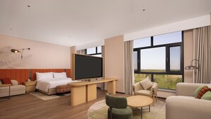 Une chambre d’hôtel équipée d’un lit, d’une télévision, d’un bureau, d’un canapé, d’une chaise et de grandes fenêtres.